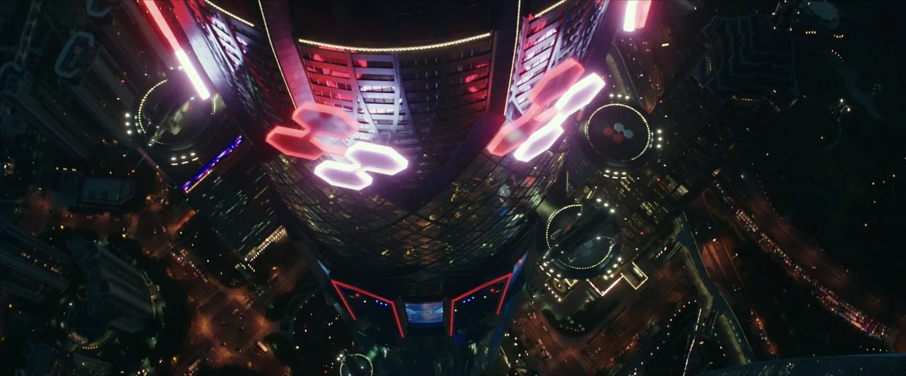 Pacific Rim: Uprising (2018) movie still: establishing — A massive, sleek skyscraper glows with neon geometric patterns in a dense nighttime…