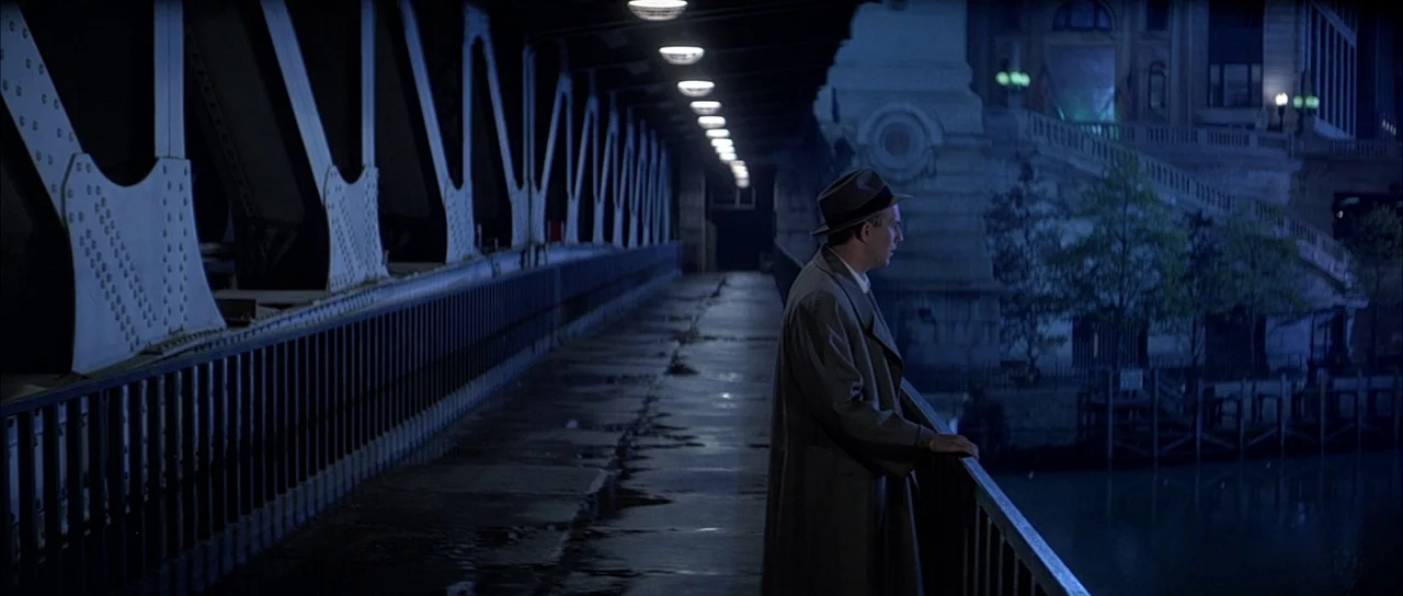 The Untouchables (1987) movie still: wide — A metal bridge spans across a dark waterway at night with illuminated street lamps. A man wearing a…