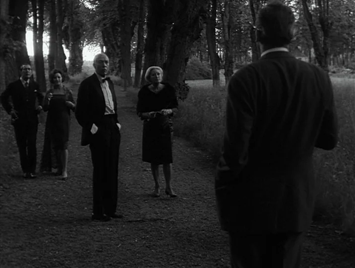 Hour of the Wolf (1968) movie still: fullbody — A gravel path lined with tall mature trees leads through a grassy field. Four people in formal…