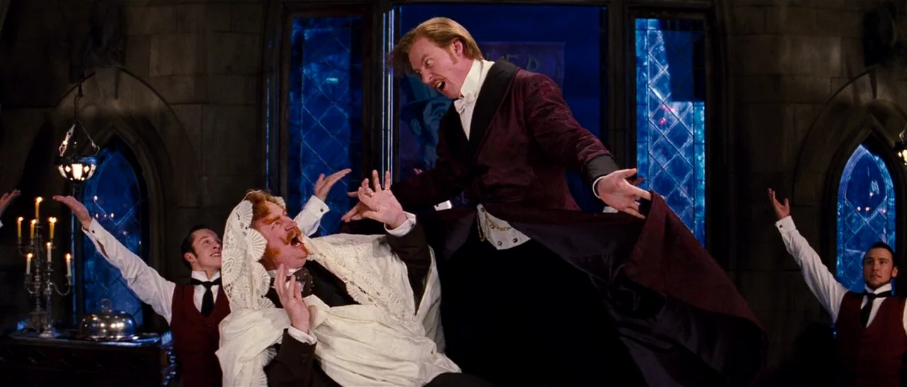 Moulin Rouge! (2001) movie still: medium — A gothic stone room features arched windows glowing with deep blue night light. Several men in formal…