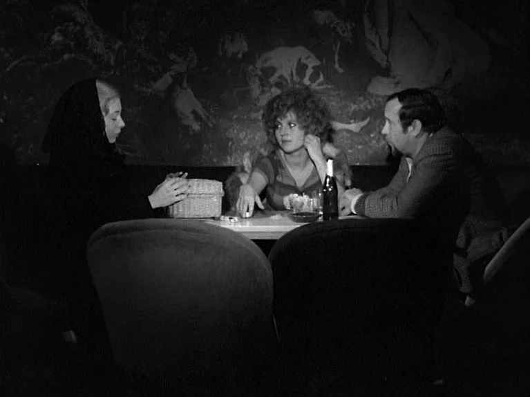 Gods Of The Plague (1970) movie still: medium — A dark, intimate nightclub booth featuring a decorative mural on the back wall. Three people are…