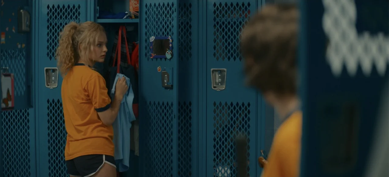 My Best Friend's Exorcism (2022) movie still: medium — A row of blue industrial lockers fills the frame in a school locker room. A blonde girl…