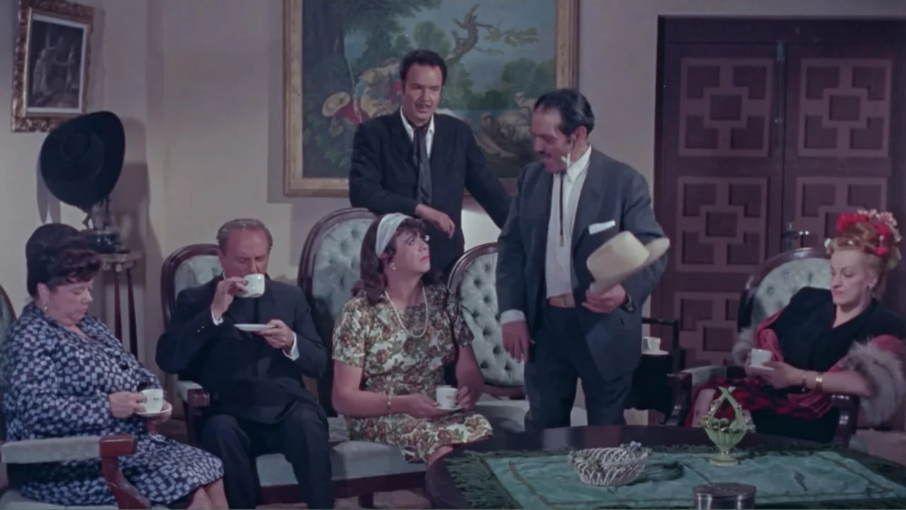 Los Dos Rivales (1966) movie still: medium — A furnished interior with classic chairs and a landscape painting on the wall. Five individuals gather…