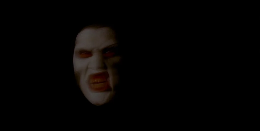 Dominion: Prequel to the Exorcist (2005) movie still: closeup — A pitch-black void surrounds the floating, pale face of a distorted human figure.…