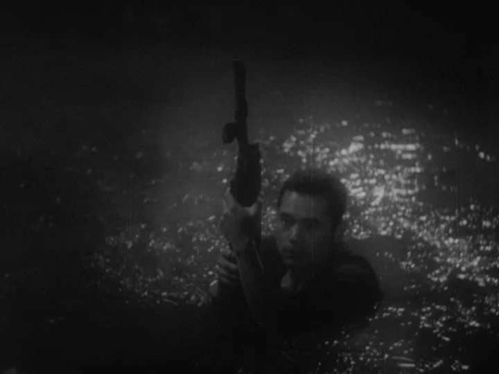 Sanshiro Sugata (1943) movie still: medium — A dark river at night with light reflecting on the rippling surface of water. A soldier emerges from…
