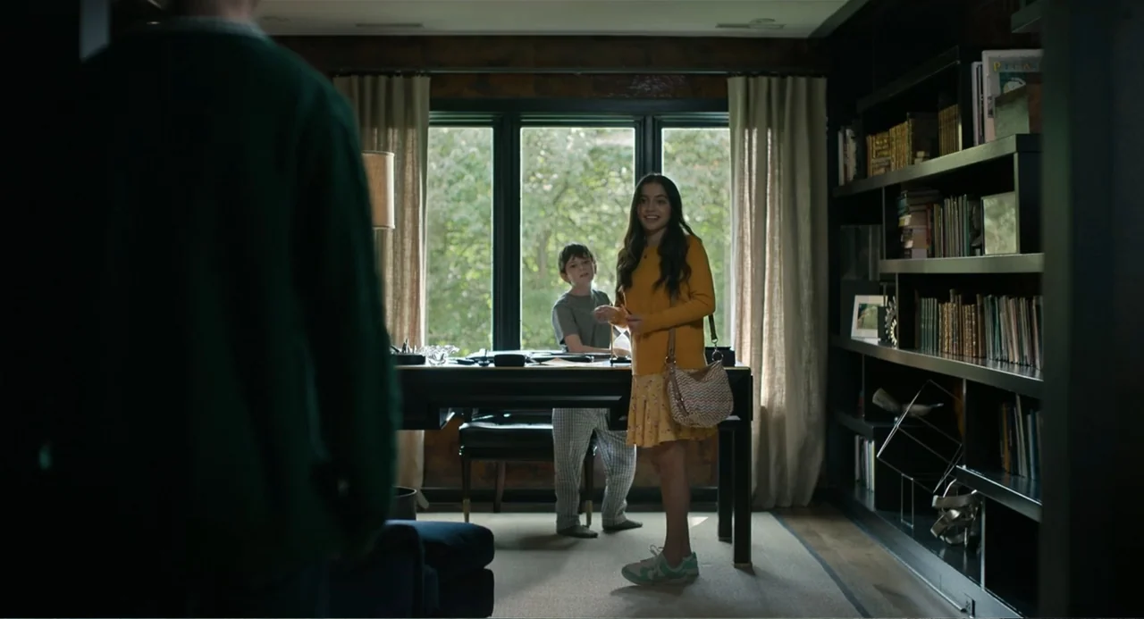 Turtles All the Way Down (2024) movie still: medium — A well-lit residential office contains a dark desk, built-in bookshelves, and large windows. A…