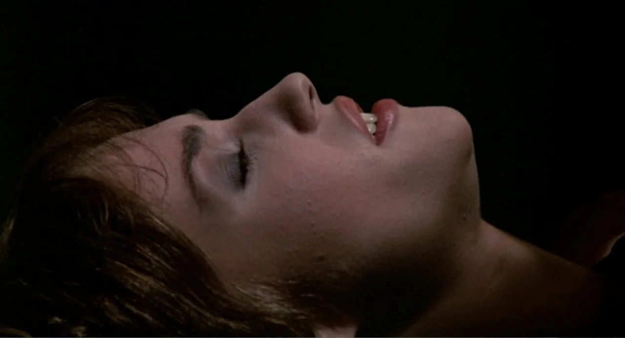 Hercules (1983) movie still: closeup — A close-up view of a woman's face resting against a dark background. She lies in a still position with her…