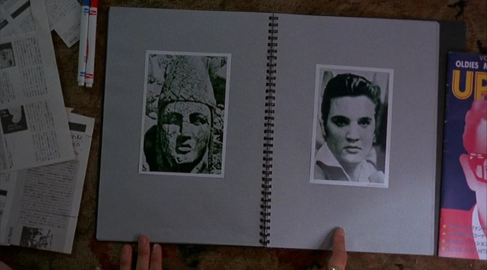 Mystery Train (1989) movie still: closeup — An open spiral-bound notebook lies flat on a textured surface alongside scattered papers. Two printed…