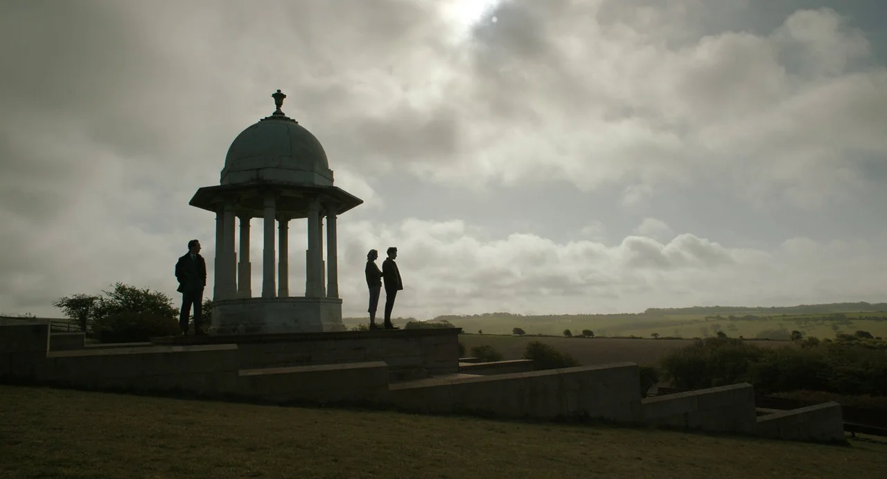 My Policeman (2022) movie still: wide — A stone domed temple sits on a hillside overlooking a vast rural landscape. Three figures are silhouetted…
