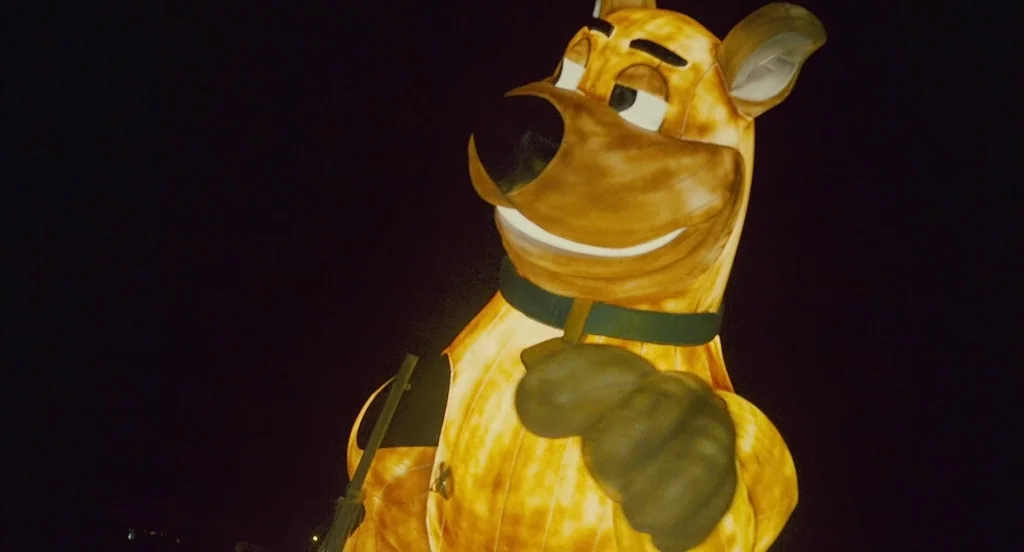 127 Hours (2010) movie still: medium — A giant inflatable Scooby-Doo balloon drifts through the night sky. The balloon is internally illuminated and…