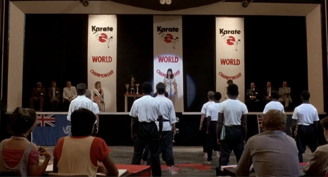 American Ninja 3: Blood Hunt (1989) movie still: wide — A gymnasium interior features three large banners advertising a world karate championship…