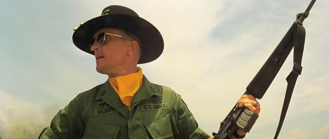 Apocalypse Now (1979) movie still: medium — A soldier stands against a bright, hazy sky on an outdoor battlefield. He holds a rifle across his chest…