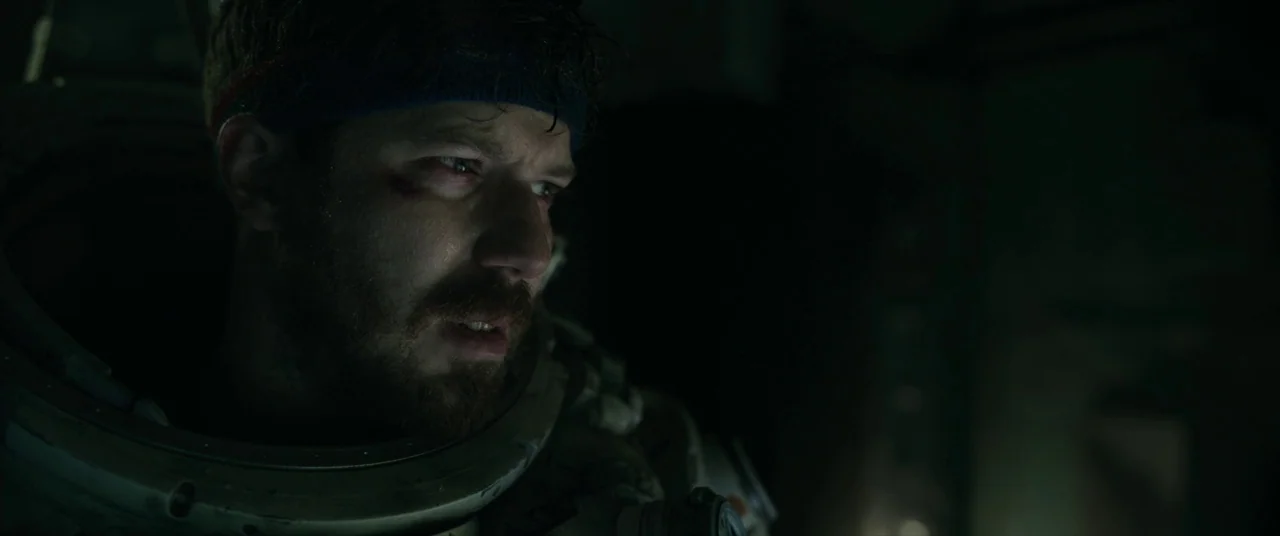 Underwater (2020) movie still: closeup — A dark, cramped environment inside a pressurized helmet with mechanical collar details visible. The subject…