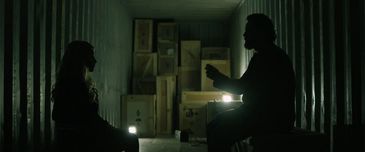 Den of Thieves 2: Pantera (2025) movie still: medium — The interior of a corrugated metal shipping container is filled with stacked wooden crates. A…