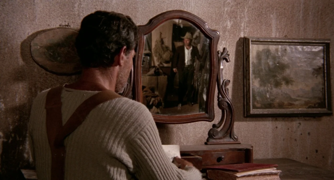 The Hellbenders (1967) movie still: medium — A rustic room features plaster walls and a vintage wooden vanity with an ornate mirror. A man wearing…