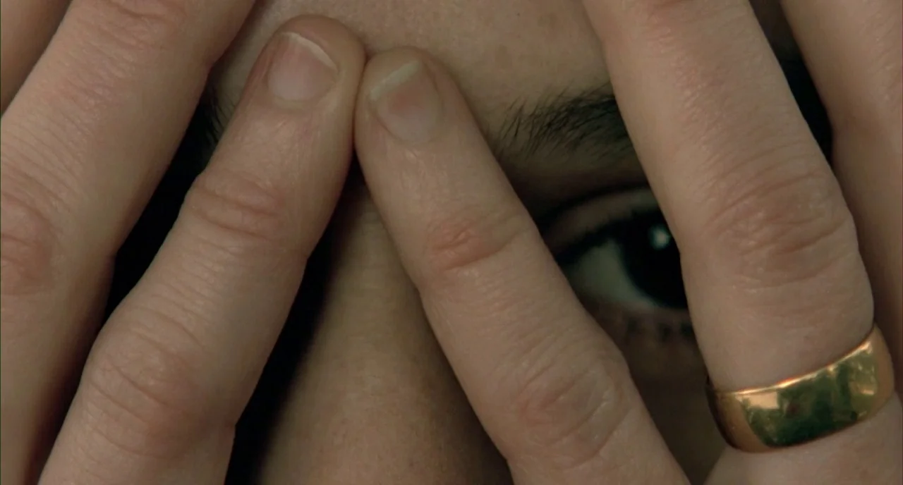 The Piano (1993) movie still: closeup — A close-up view shows a person's hands positioned over their face. Fingers are spread wide, obscuring most…