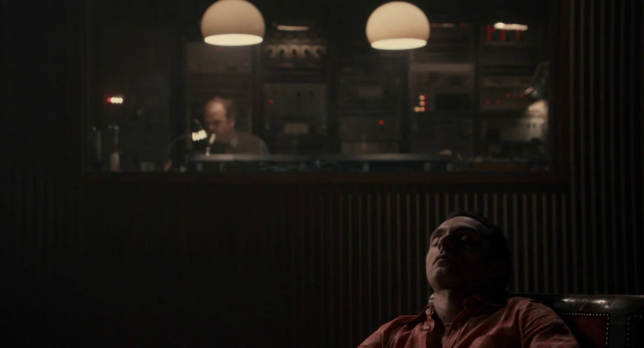 Berberian Sound Studio (2012) movie still: medium — A dark recording studio room features a control booth visible through a large window. A man in…