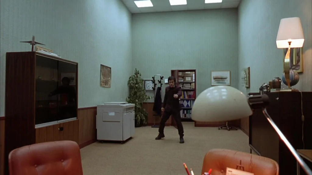 The Science Of Sleep (2006) movie still: wide — A sterile professional workspace features pale green walls and beige carpeting. A lone man stands in…