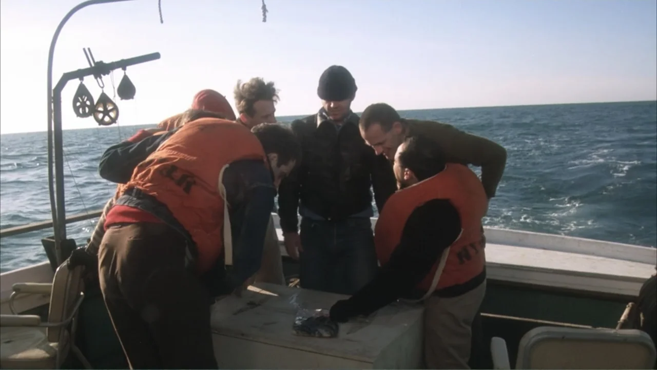 One Flew Over the Cuckoo's Nest (1975) movie still: medium — A group of men wearing life vests gather on the deck of a boat. They are huddled…