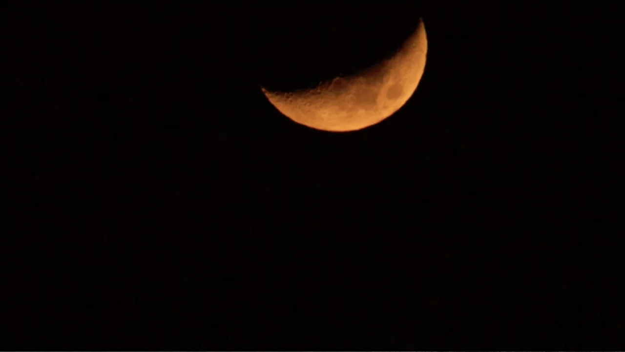 Alien Sharks: Ghosts of Japan (2024) movie still: establishing — A bright orange crescent moon hangs in the dark night sky. No other subjects or…
