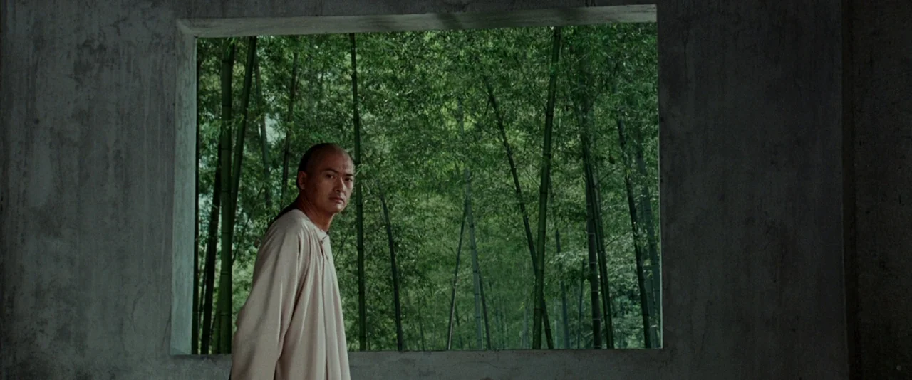 Crouching Tiger, Hidden Dragon (2000) movie still: medium — A man in a pale robe stands in a dark concrete room. Through a large square window…