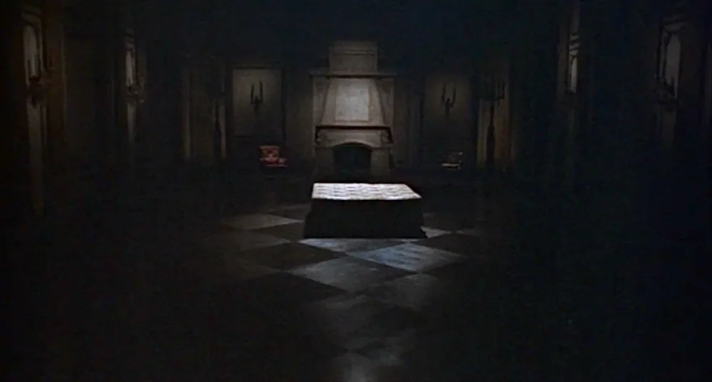 Rosemary’s Baby (1968) movie still: wide — A vast, dim hall features a stone fireplace and dark paneling on the walls. A low, rectangular platform…