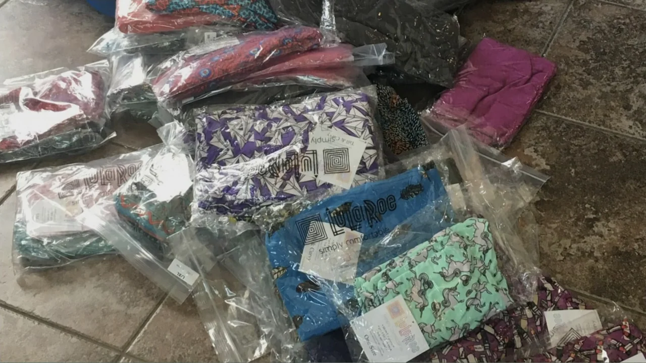 The Rise and Fall of Lularoe (2021) movie still: wide — A pile of assorted leggings in clear plastic bags sits on a tiled floor. The garments…