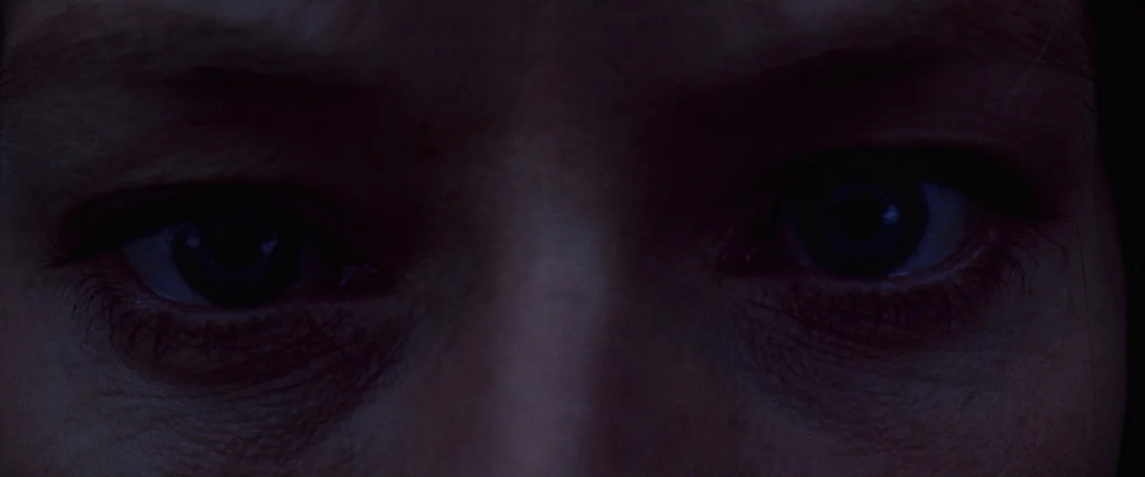 Contact (1997) movie still: closeup — Extreme closeup of a woman's eyes in a very dark setting. The subject stares ahead with a steady, unmoving gaze.