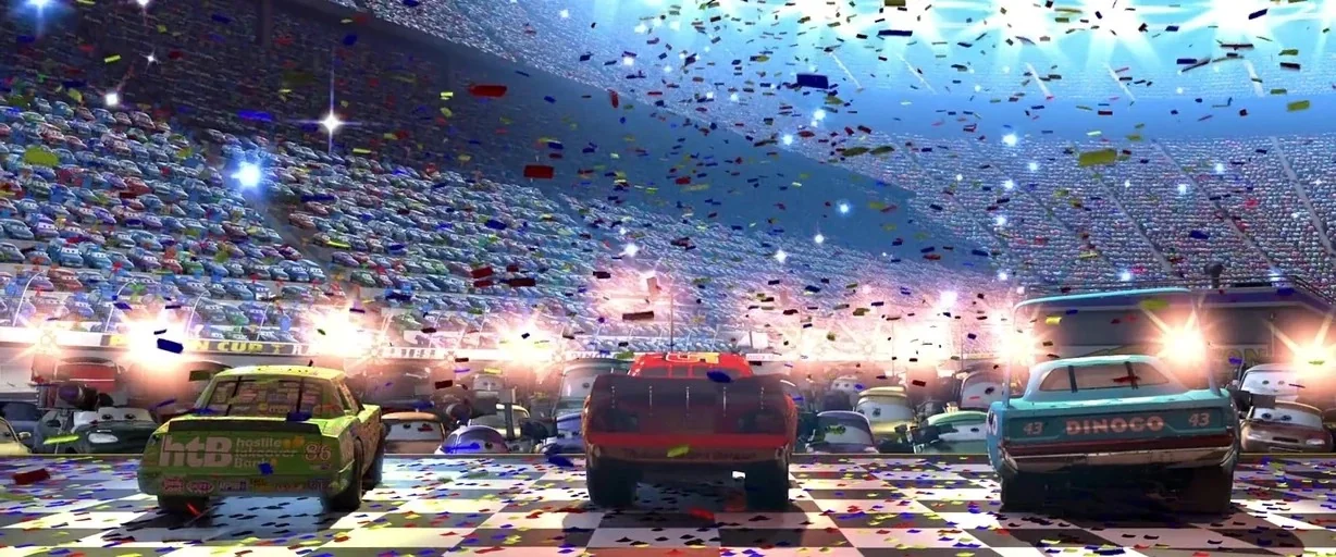 Cars (2006) movie still: wide — A crowded stadium grandstand filled with animated spectators surrounds a finish line track surface. Colorful…
