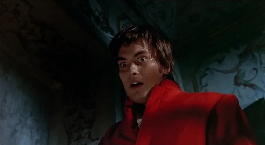 Lisa and The Devil (1973) movie still: medium — A dimly lit interior space features ornate, dark walls with faint decorative patterns. A young man…