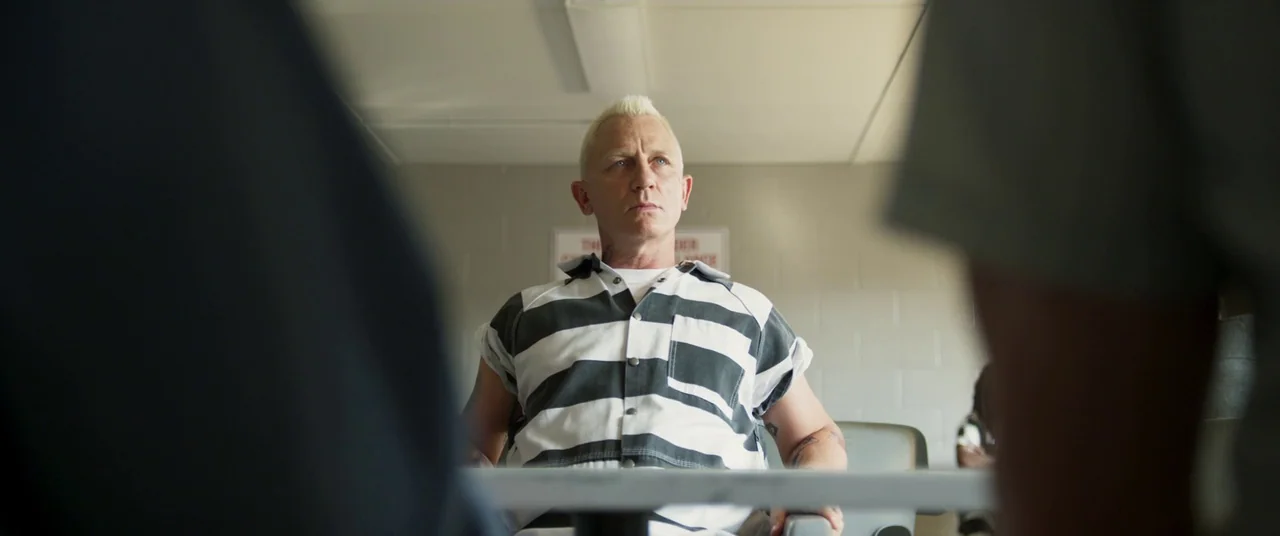 Logan Lucky (2017) movie still: medium — A spartan visitation room with light grey concrete block walls and white ceiling tiles. A man in a prison…