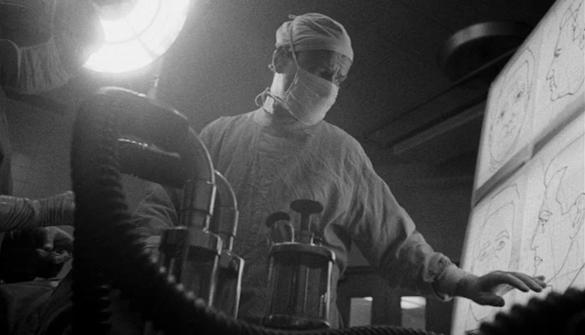 Seconds (1966) movie still: medium — A dimly lit room features a glowing panel displaying detailed anatomical or facial sketches. A surgeon in…