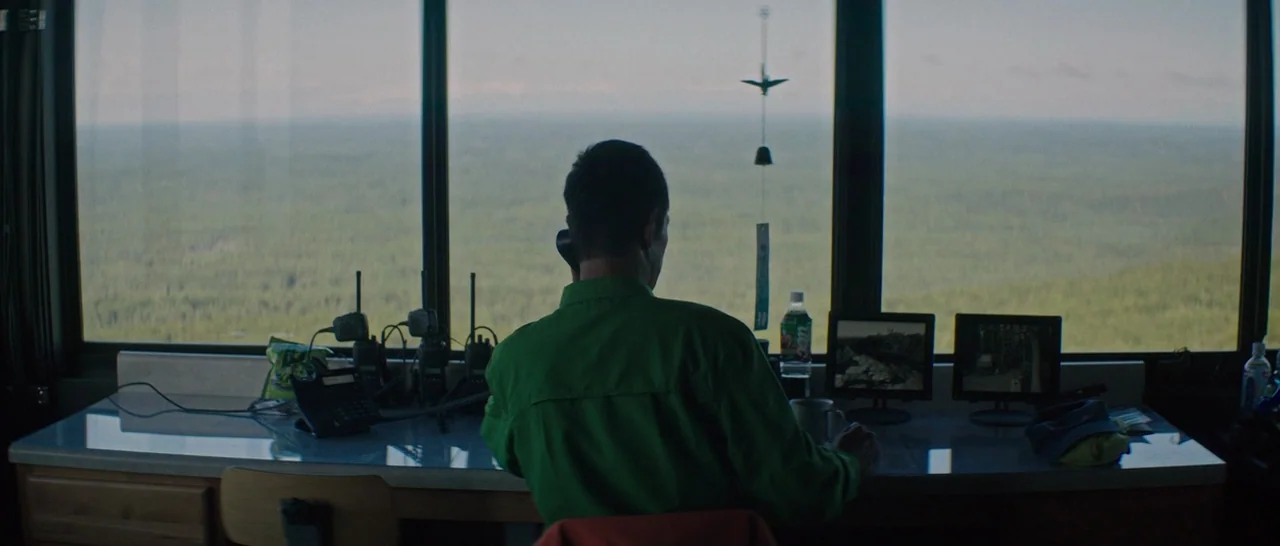 The Sea of Trees (2015) movie still: medium — A high-altitude room features large panoramic windows looking out over a vast forest canopy. A man in…
