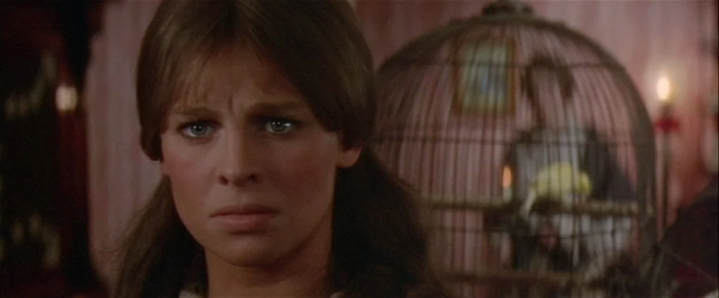 Far from the Madding Crowd (1967) movie still: closeup — A dimly lit room with wallpapered walls and a prominent birdcage in the background. A young…