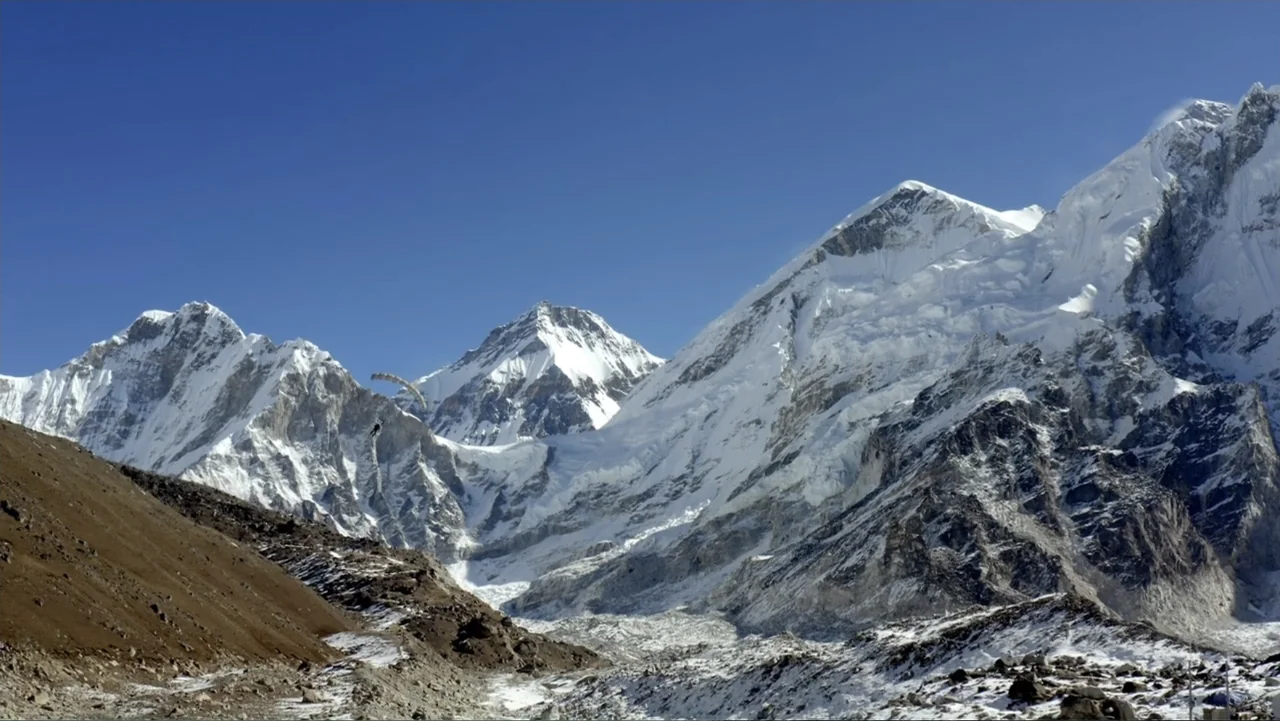 Drop Zone Everest (2023) movie still: wide — A vast mountain range with massive snow-capped peaks dominates the landscape. The scene is…