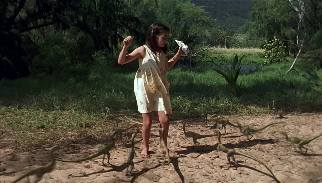 The Lost World: Jurassic Park (1997) movie still: fullbody — A clearing surrounded by dense jungle foliage and trees under bright daylight. A young…