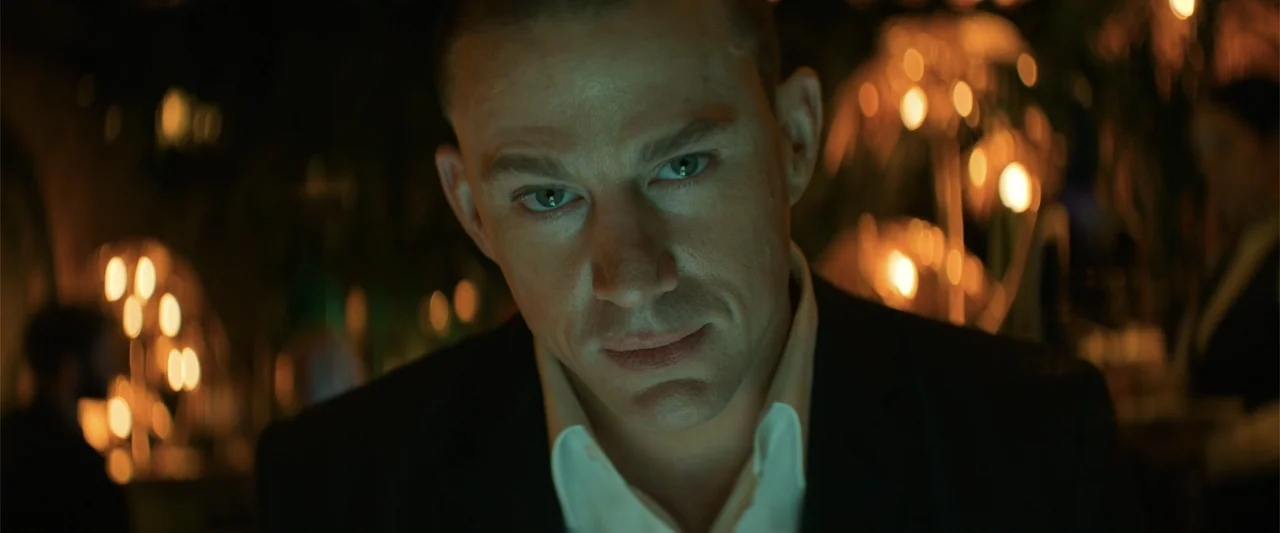 Magic Mike's Last Dance (2023) movie still: closeup — A dimly lit upscale restaurant interior features bokeh light sources in the blurry background.…