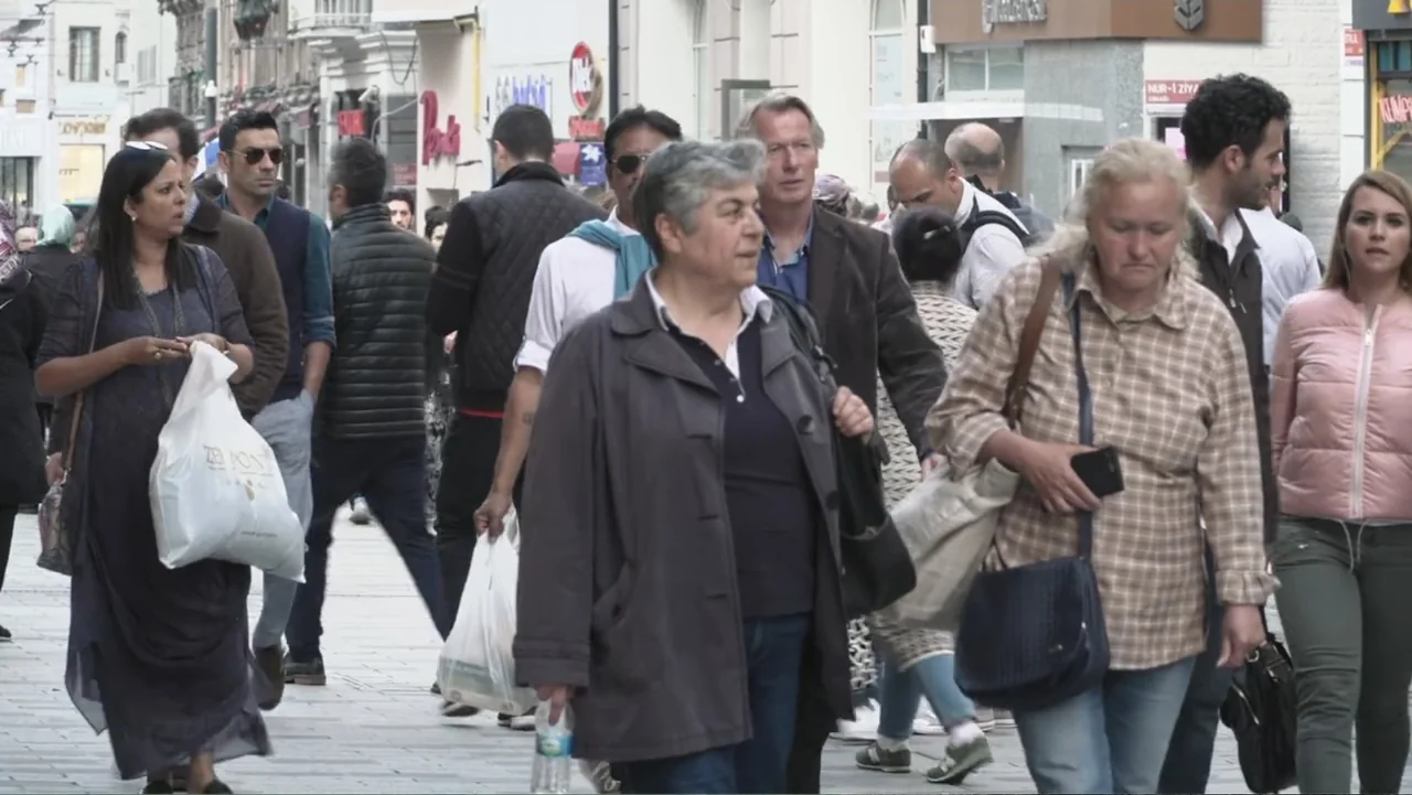 A Gift from God (2019) movie still: fullbody — A busy urban pedestrian thoroughfare features various shoppers walking towards the camera lens.…
