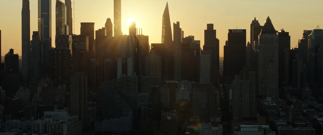 Spider-Man: No Way Home (2021) movie still: establishing — A dense urban skyline consists of various modern high-rise buildings under a sunset sky.…