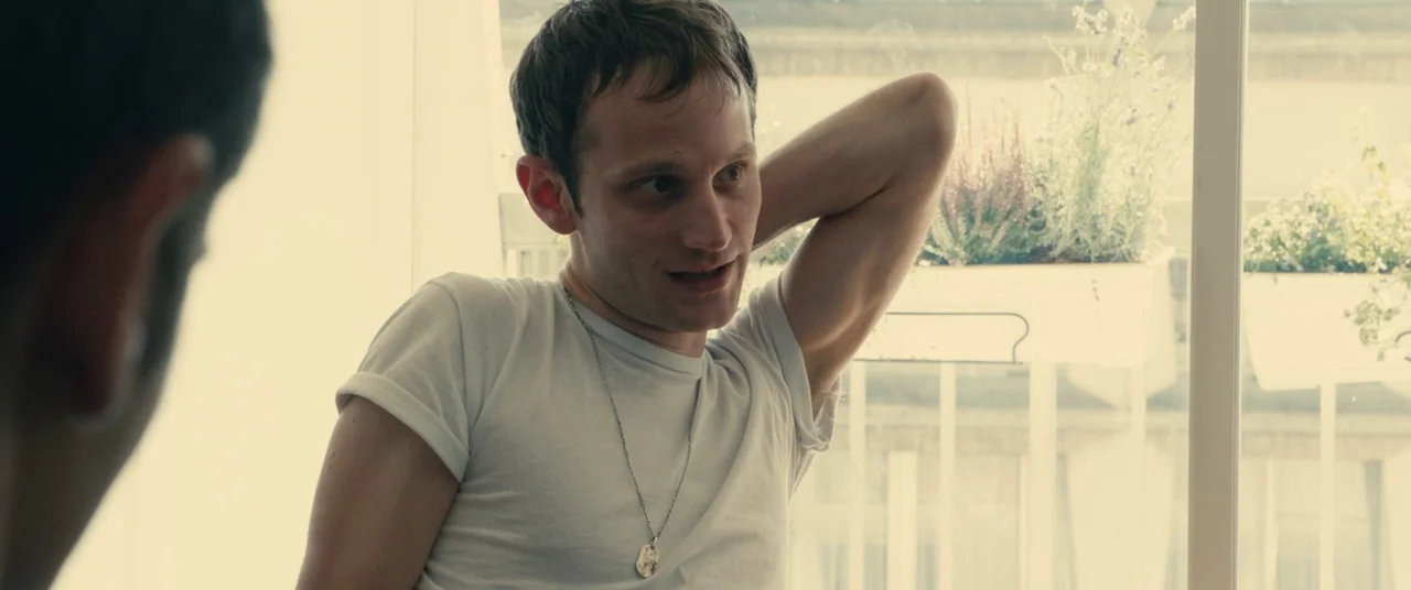 BPM (Beats Per Minute) (2017) movie still: medium — A bright living space features a large window with potted plants on the sill. A man in a white…