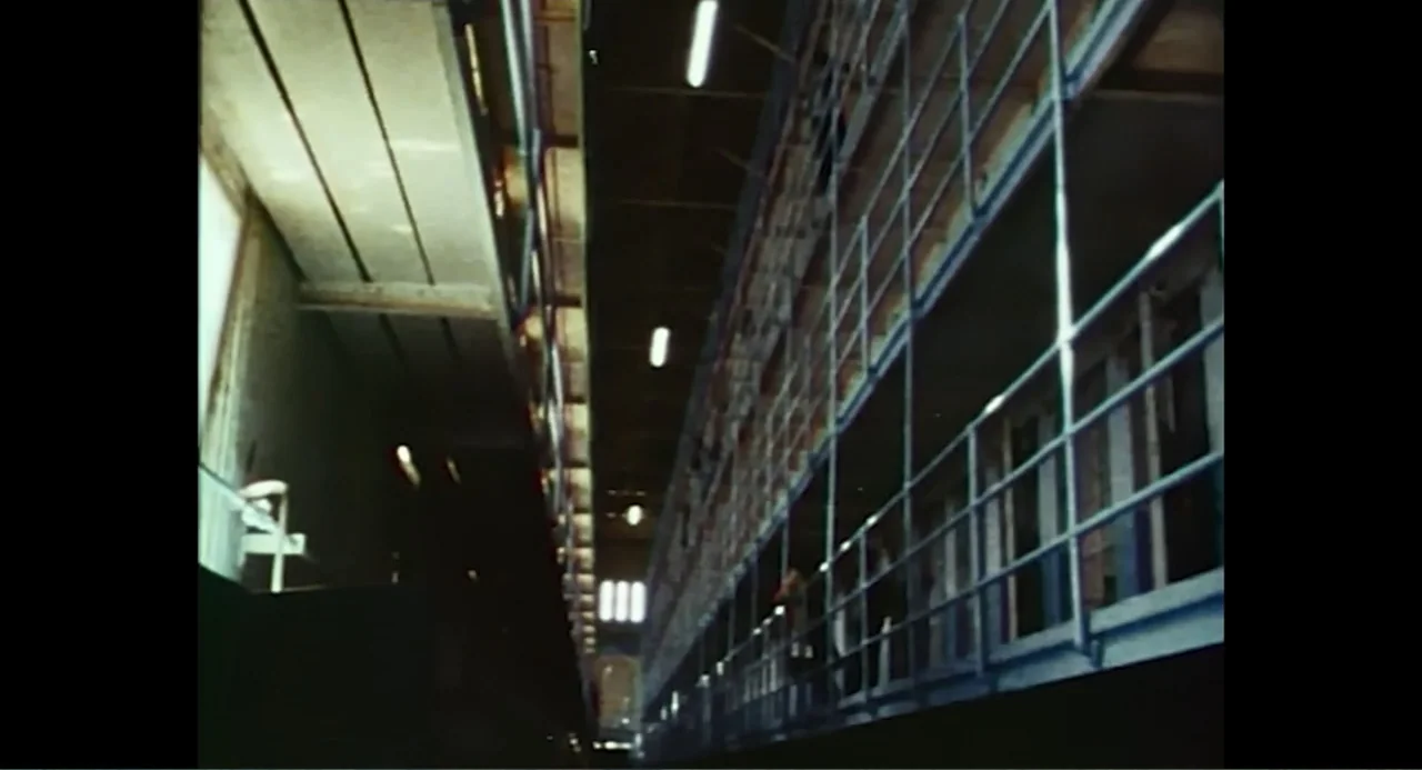 Free Chol Soo Lee (2022) movie still: establishing — A multi-level prison cell block with industrial metal railings and concrete walkways. The long,…