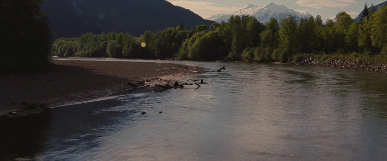 The Twilight Saga: Breaking Dawn – Part 1 (2011) movie still: establishing — A wide river flows through a dense forest flanked by high snow-capped…