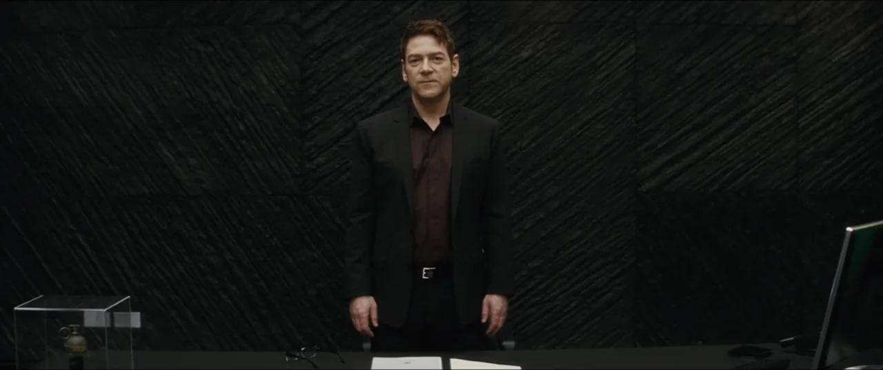 Jack Ryan: Shadow Recruit (2014) movie still: medium — A man stands before a wall with dark textured panels inside an office space. He is positioned…