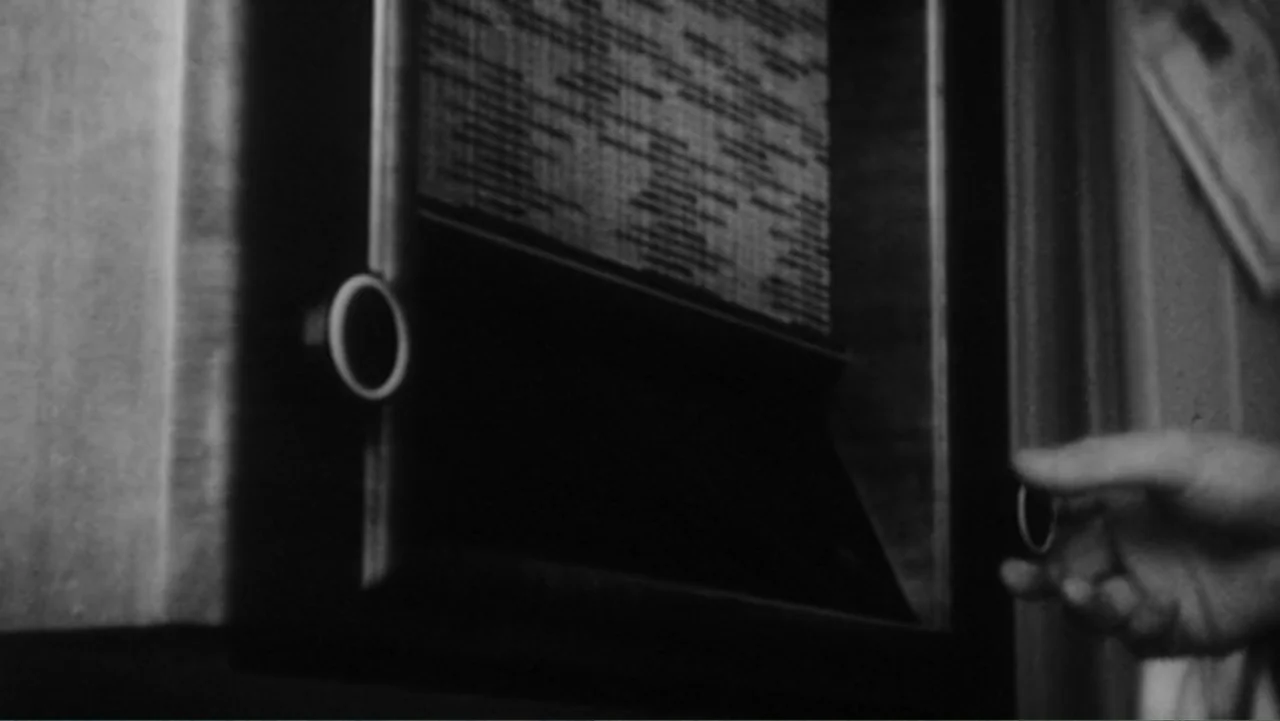 Mr. Dressup: The Magic of Make Believe (2023) movie still: closeup — A close-up of a vintage wood-paneled radio dial in a darkened interior room. A…