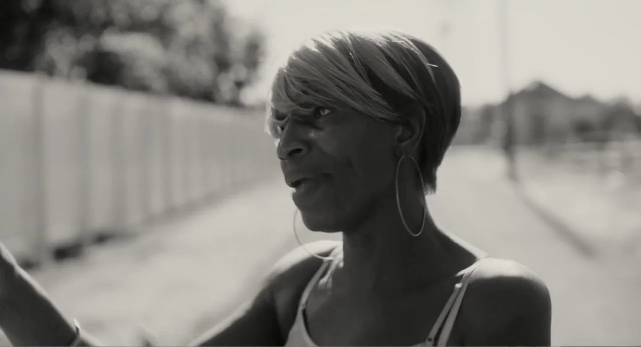 What You Gonna Do When the World's on Fire? (2019) movie still: closeup — A sunny outdoor sidewalk with a blurred fence and buildings in the…