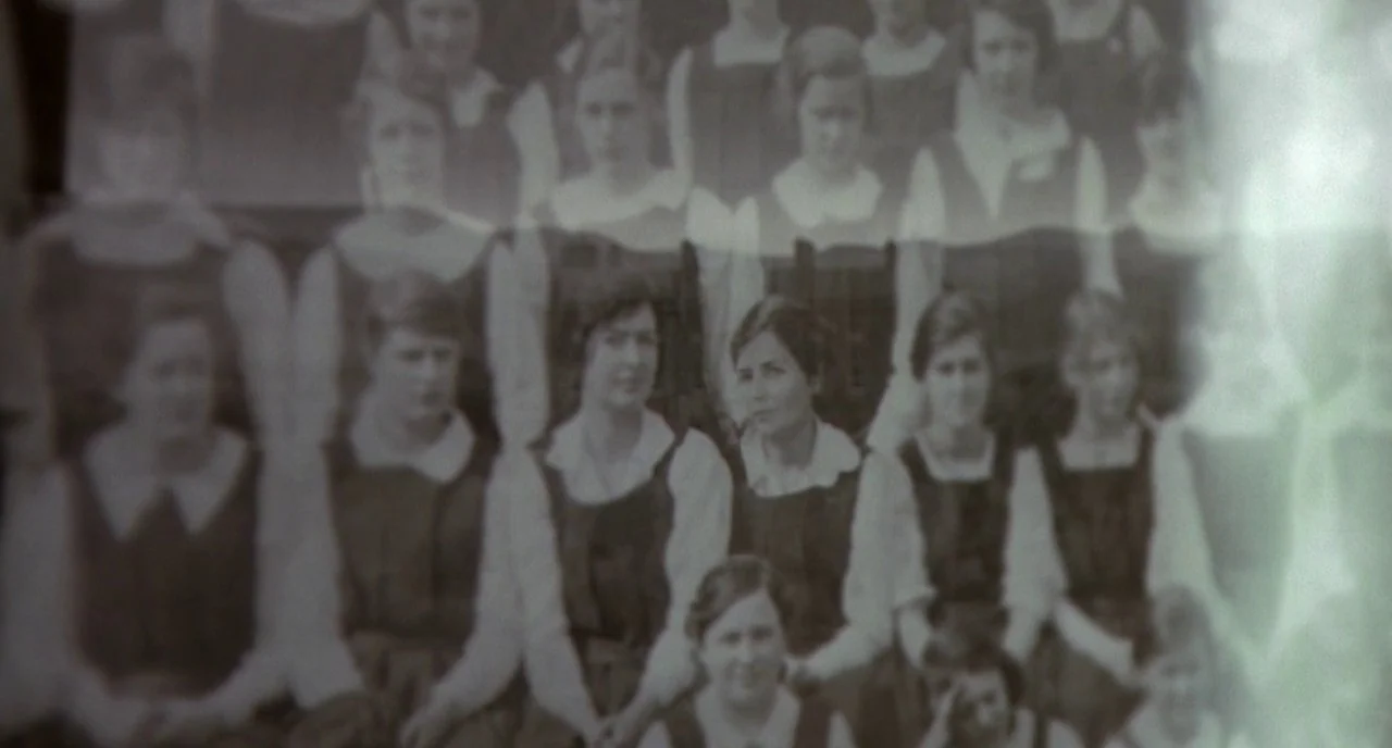 Cracks (2009) movie still: medium — A group of teenage girls pose for an old class photograph in rows. They are dressed in uniform school outfits…