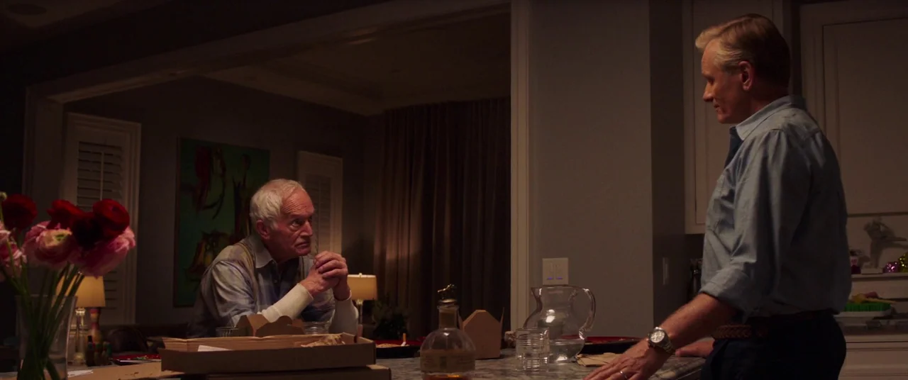 Falling (2020) movie still: medium — A modern home interior with an open kitchen island and a living area background. Two men are having a…