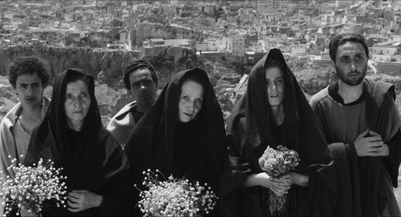 The Gospel According To St. Matthew (1964) movie still: medium — An arid, elevated terrain overlooks a dense cluster of ancient stone dwellings. Six…