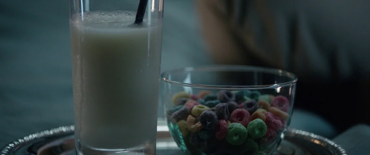 Get Out (2017) movie still: closeup — A glass of milk with a straw and a bowl of colorful cereal.