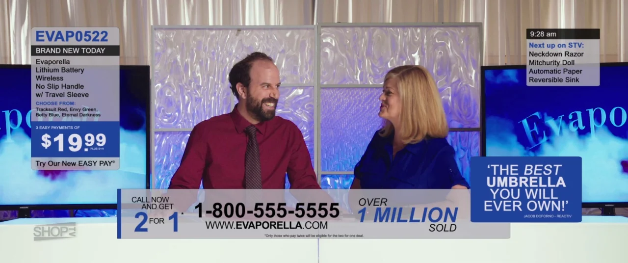 Room For Rent (2017) movie still: medium — A television shopping channel studio set features a white desk and frosted glass panels. Two hosts sit…